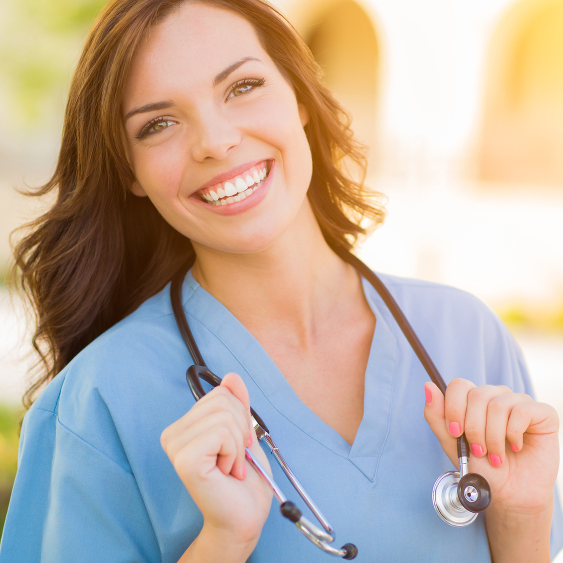 Portrait of Young Adult Female Doctor or Nurse Wearing Scrubs and Stethoscope Outside.